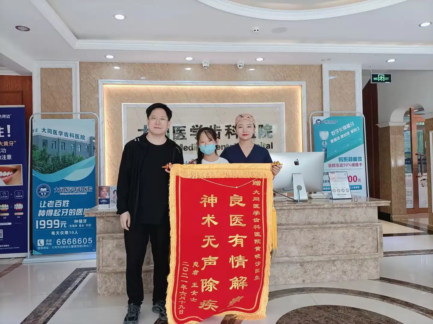 患者家属与医护人员展示致谢锦旗的合影